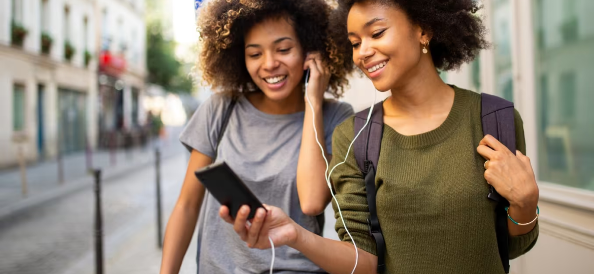 Two_women_happily_share_an_audiobook_as_they_walk_down_the_street (1)